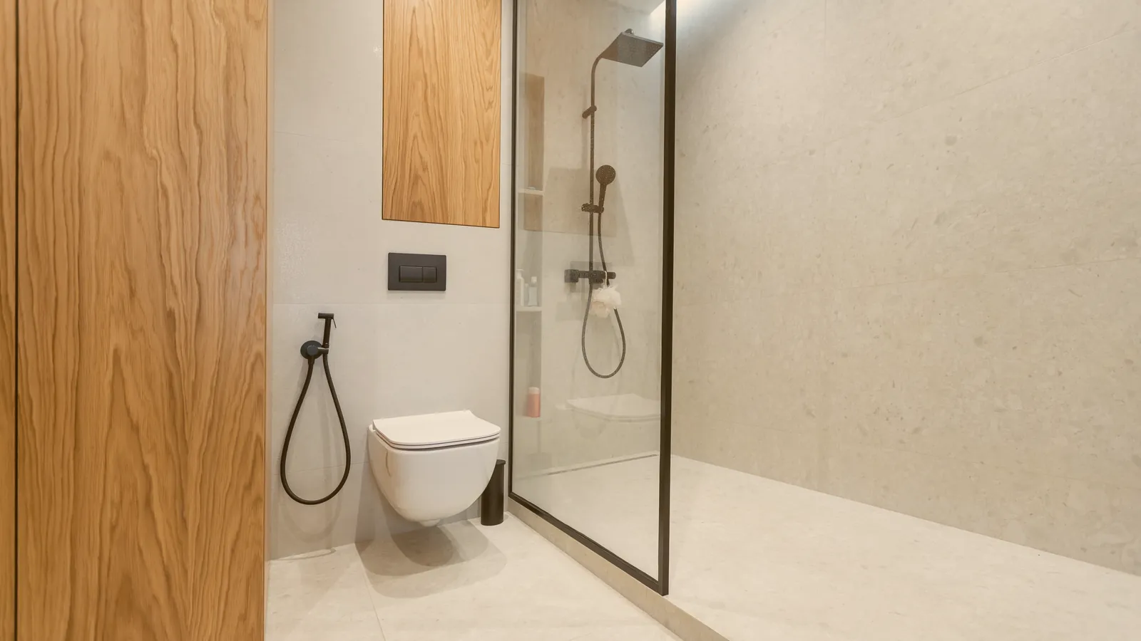 Baño moderno reformado con ducha de cristal, revestimientos neutros y mueble suspendido